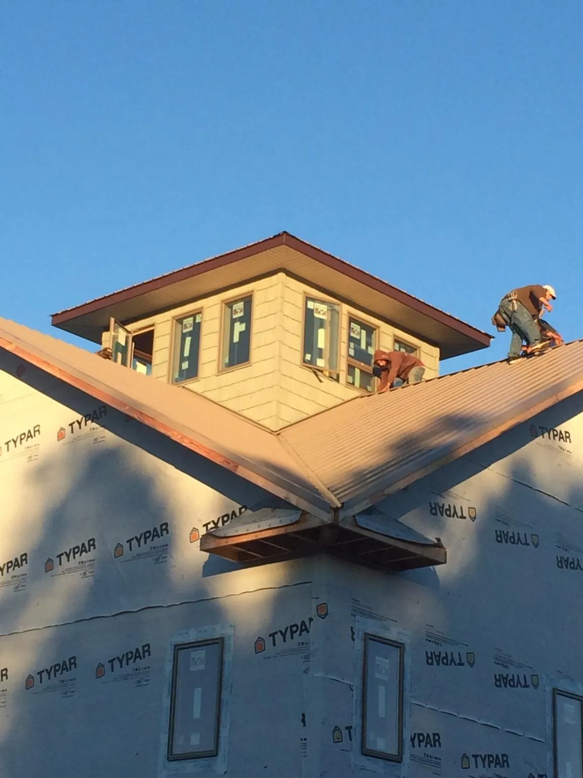 Roofers working around a rooftop cupola on a new metal roof at sunset — Roof Waterproofing in Alva by Roofing Brothers